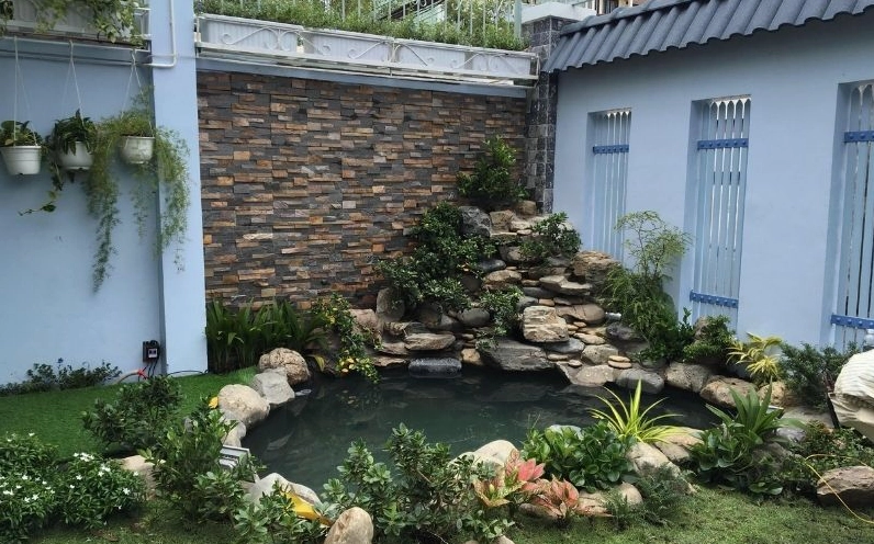 Hòn non bộ phong thủy với núi đá vững chãi và mảng xanh tạo cảm giác bình an cho nhà vườn