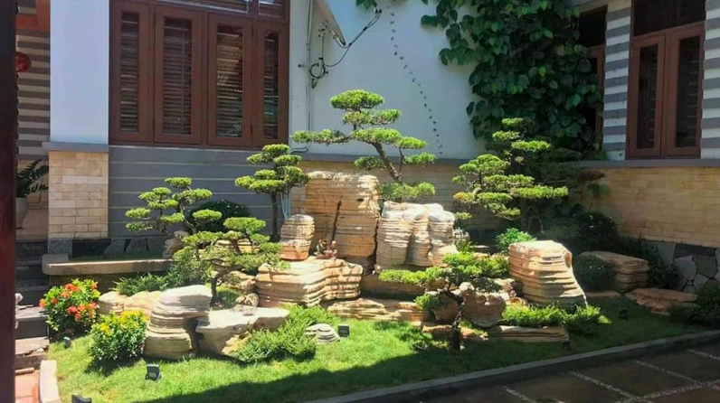 Mẫu hòn non bộ sân vườn đầy nắng với cây xanh và đá núi nổi bật trong bối cảnh ngoài trời